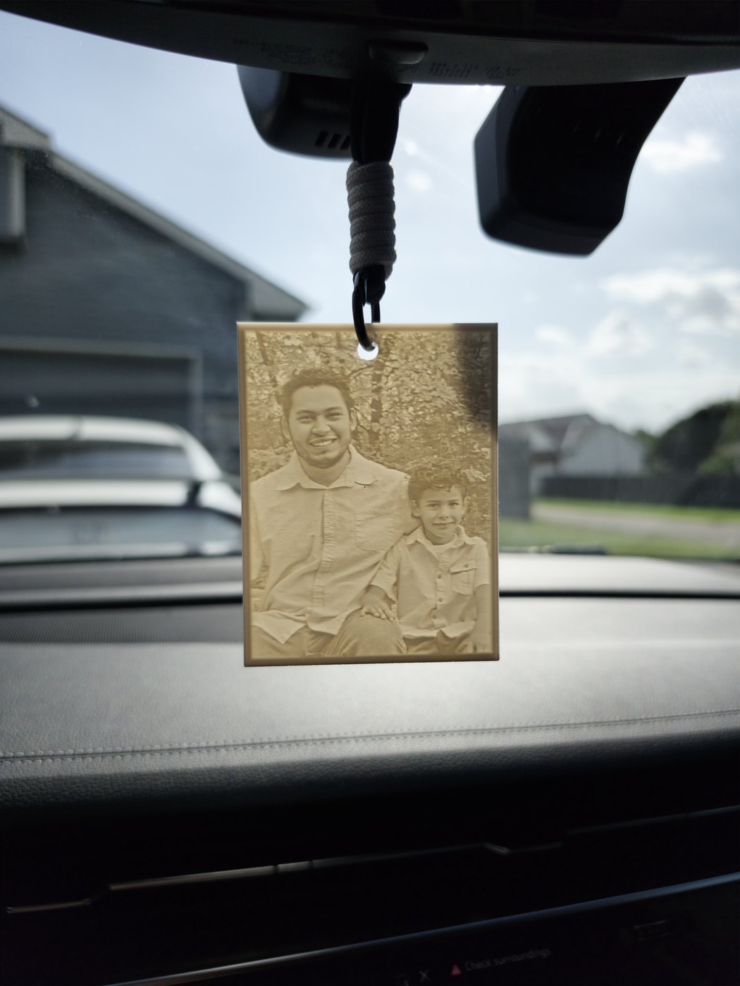 Car lithophane of a dad and son hanging from a rearview mirror by its string through the hanger hole