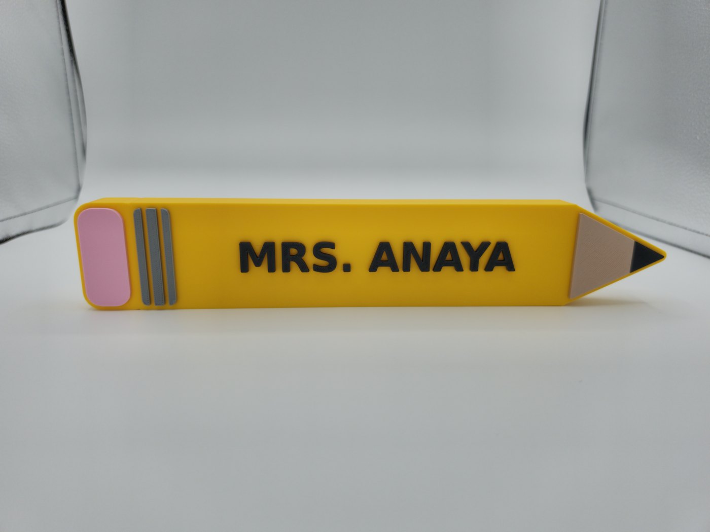 3D-printed pencil teacher sign reading MRS. ANAYA in Savannah Yellow with a Sakura Pink eraser
